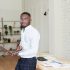 Handsome african american businessman in shirt and dress pants uses laptop and looking at camera, smiling while working in office.